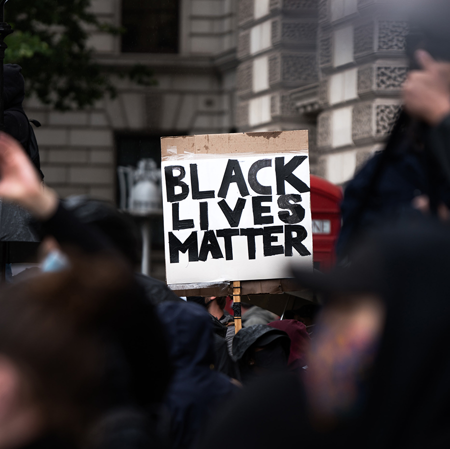 A sign at a outdoor gathering says Black Lives Matter.