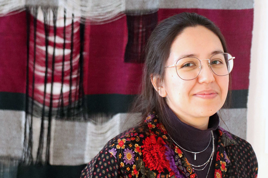  Portrait of Alicia DeVrio against a red, black and white textile that she created.