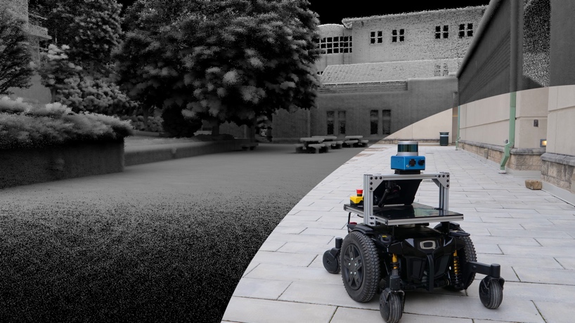A small robot that looks like a laptop perched on a robot vacuum travels a brick walkway near a building. The right side of the photo is the actual building and patio, while the left is shown in gray as areas the robot is mapping.