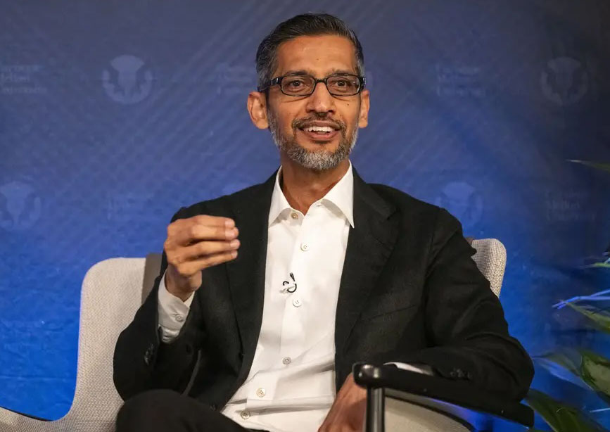  Portrait of Sundar Pichai sitting in a cream-colored chair in front of a blue screen.