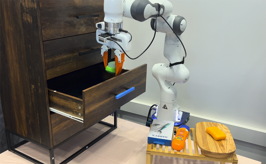  A white robotic arm puts a green brush into a dresser drawer.