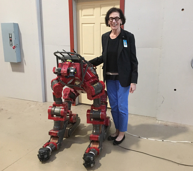 Portrait of Patti Rote posing with a large red robot.