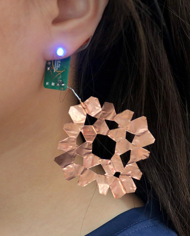  A close-up shot of an earring in human's ear, attached to a circuit board.