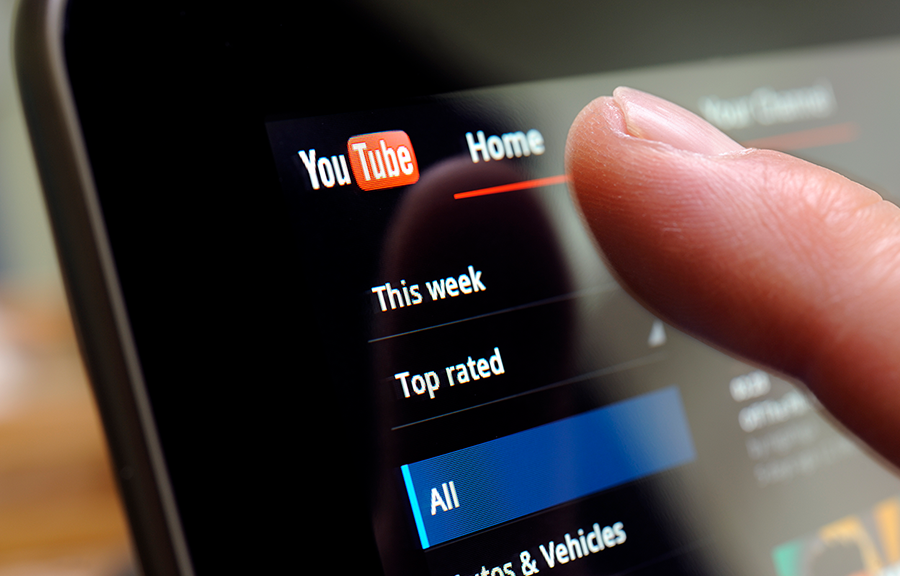  A thumb hovers over a YouTube icon on a mobile phone.