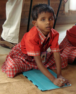 Visually-impaired student using a plastic slate and stylus to write braille